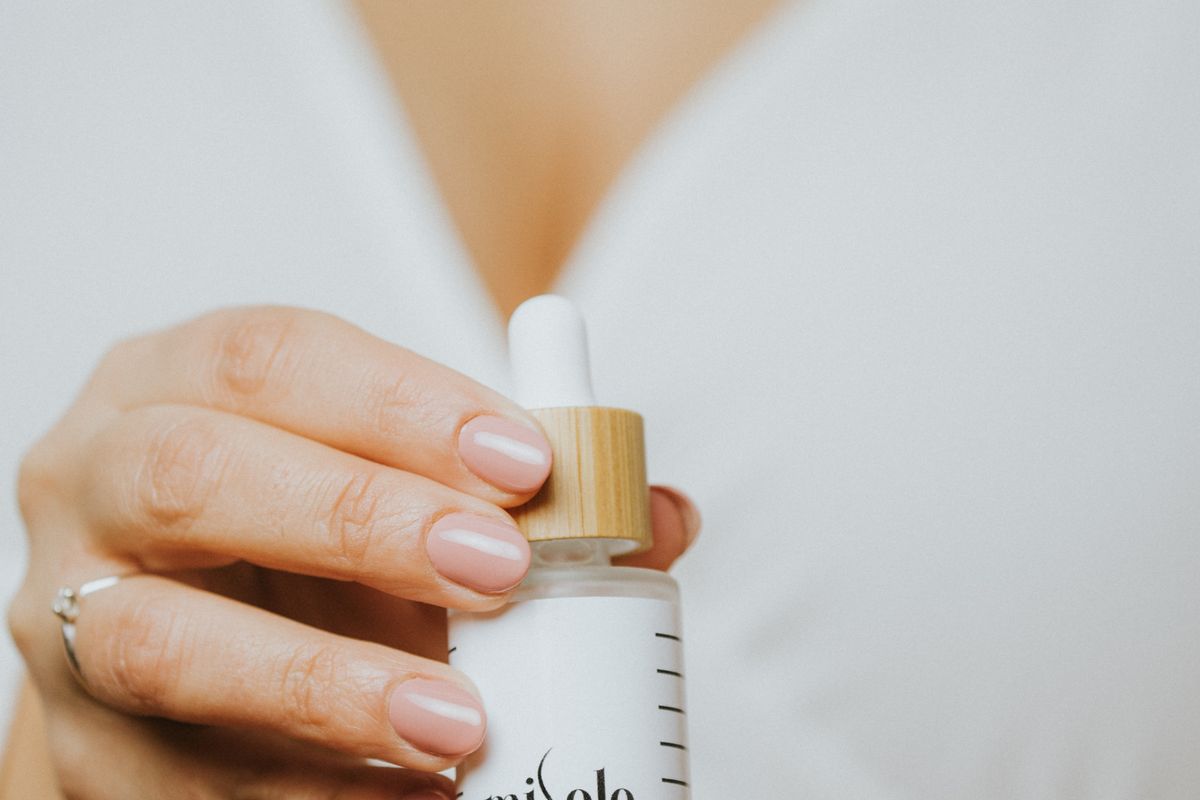 Main tenant un flacon de soin cosmétique à pipette
