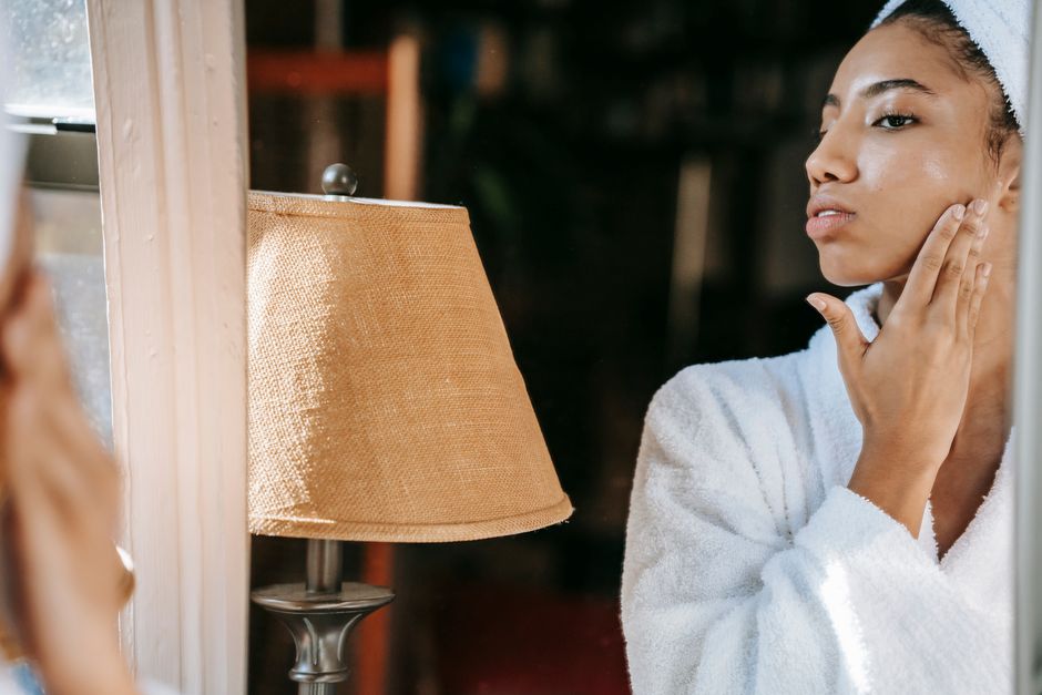 Femme touchant sa joue devant un miroir dans une lumière douce