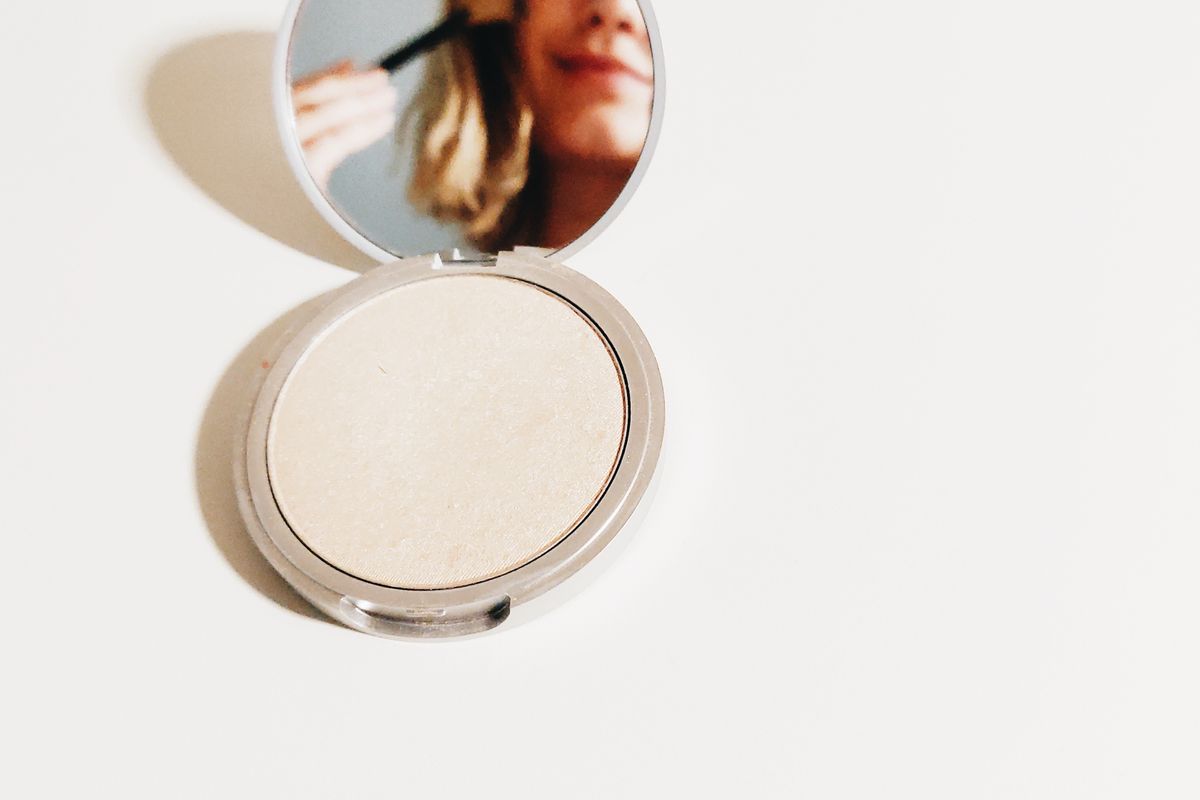 Poudre cosmétique compacte ouverte avec son miroir sur fond clair